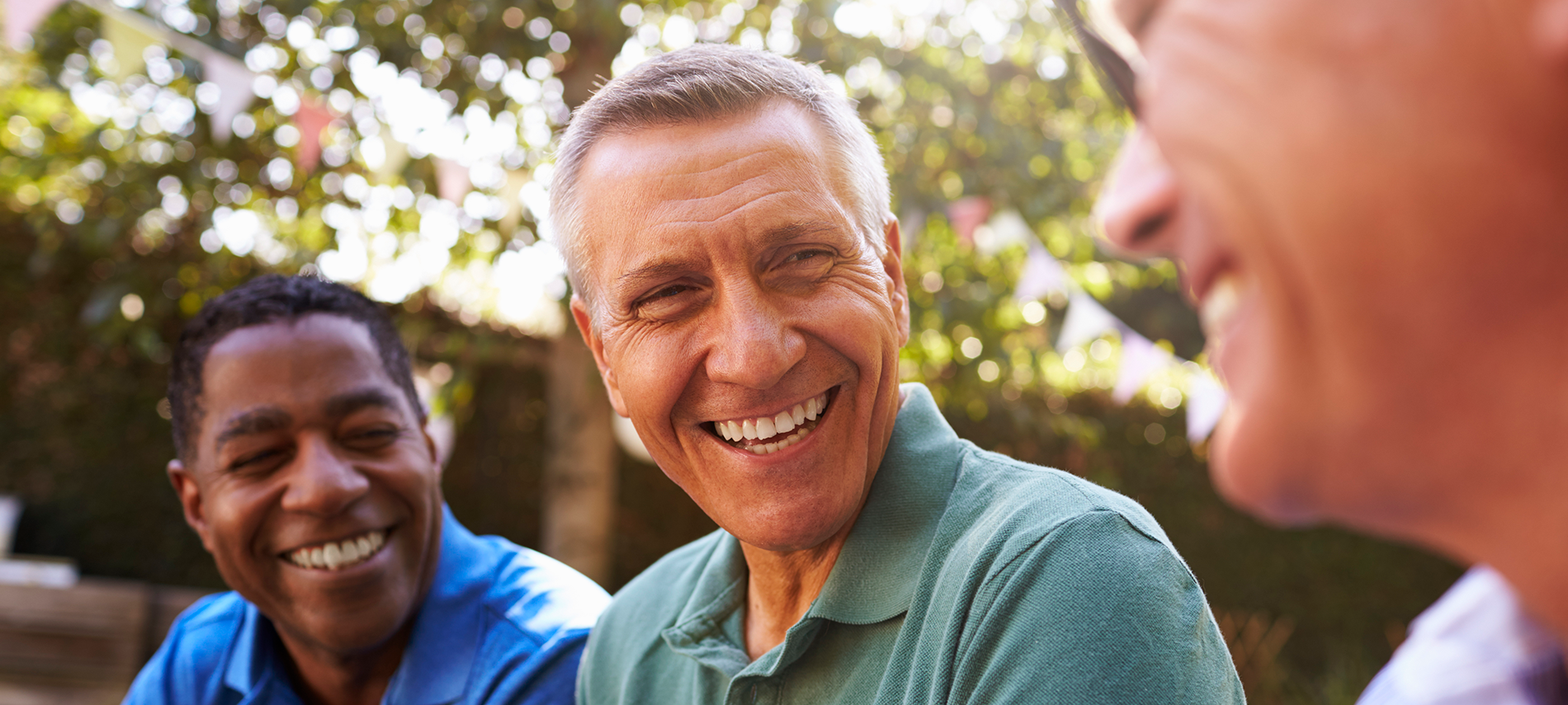 Three older men sitting around smiling at each other.