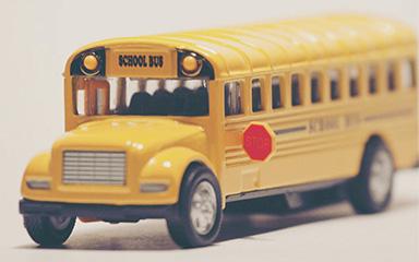 Yellow school bus figurine with a white background. 