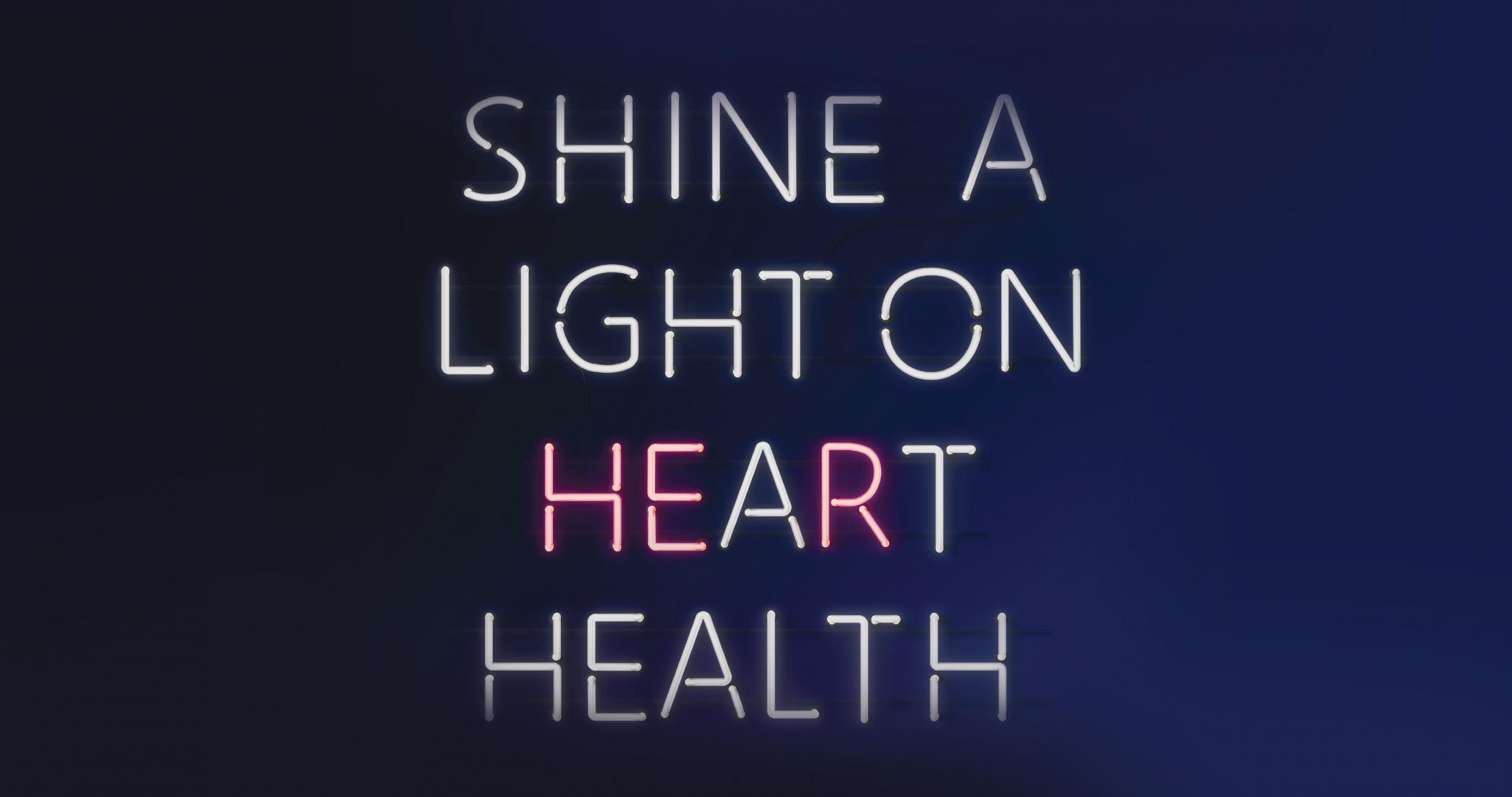 A purple gradient background with neon sign lettering that says, “Shine A Light On Heart Health."